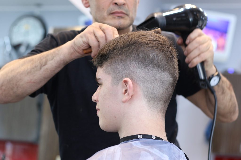 barbero utilizando secador de pelo en cita agendada con un software para barberos gratis