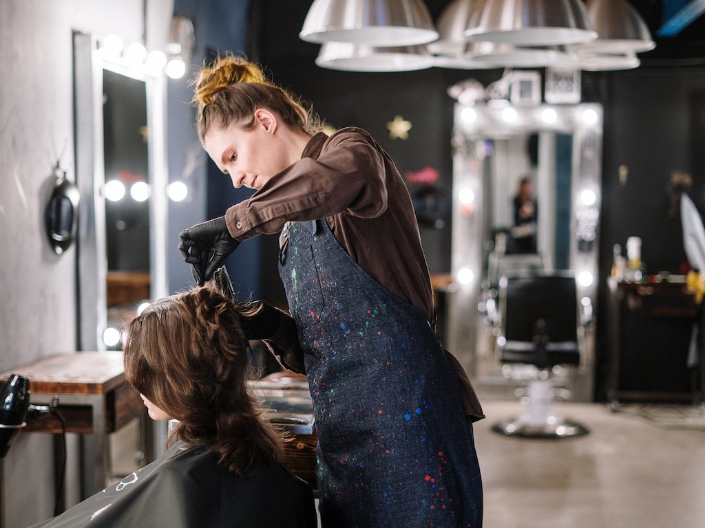 estilista haciendo un peinado que fue agendado mediante un software para salones de belleza